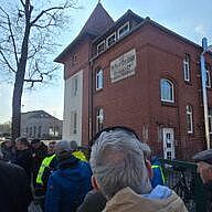 Menschen stehen vor einem Backsteinhaus